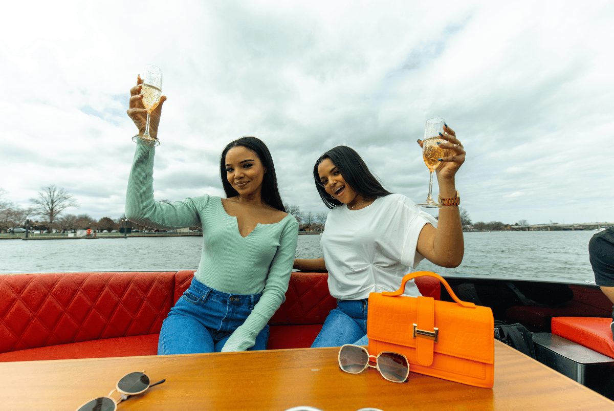 Two friends raising champagne flutes to toast on a private Yachtsy cruise